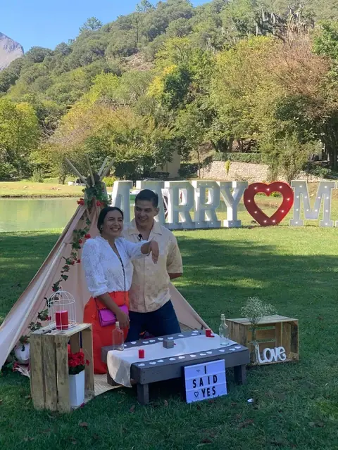 Pedida de mano montada junto al lago, con carpa, letras luminosas y la sierra al fondo