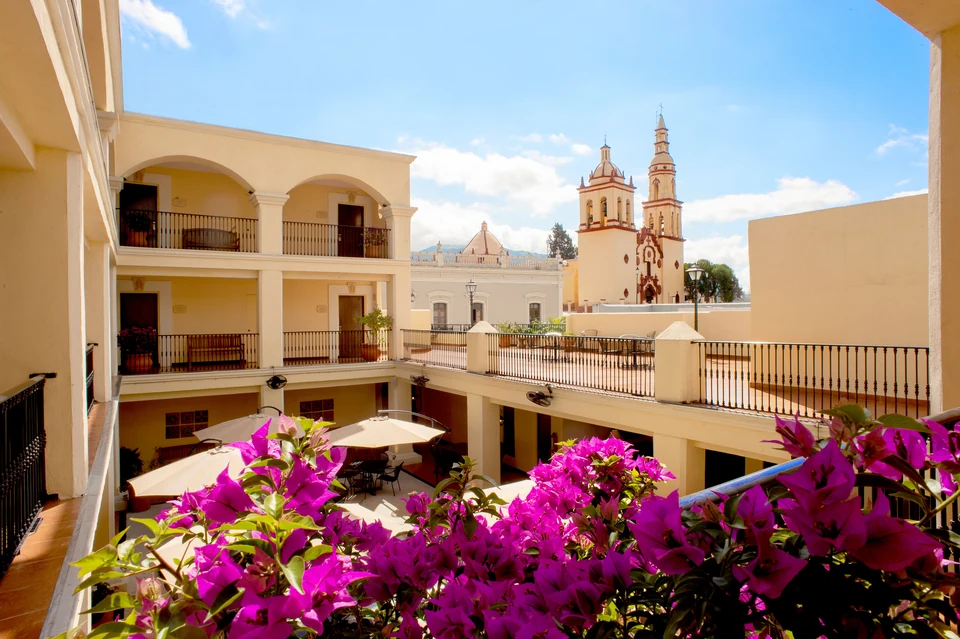 Balcones del hotel con buganvilias y las torres de la parroquia al fondo