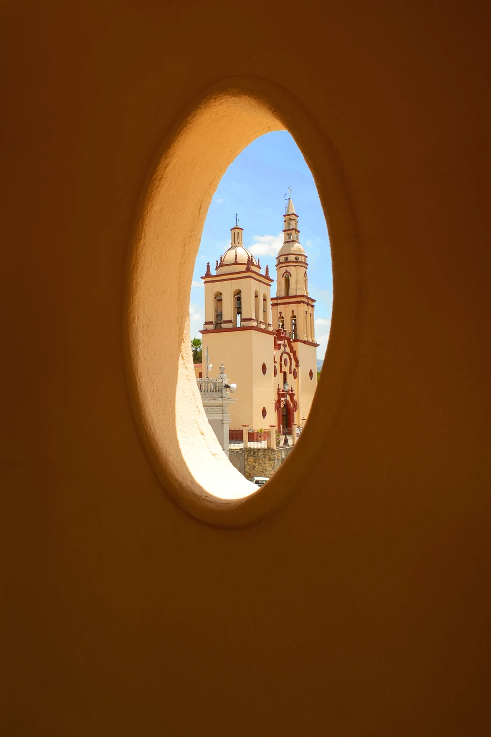 Ventana ovalada del hotel enmarcando las torres de la parroquia de Santiago